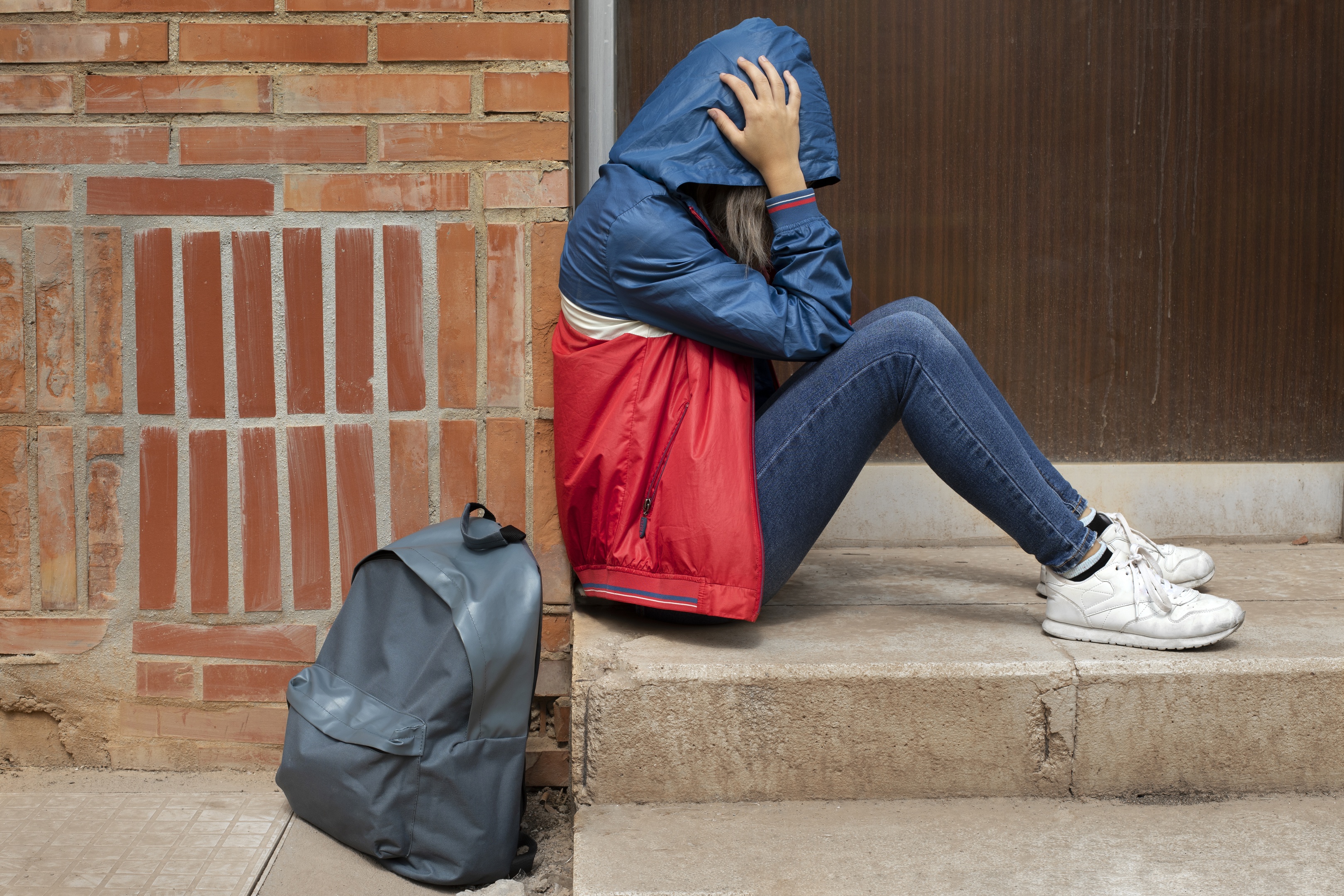 A girl sitting down in pain from being bullied at school